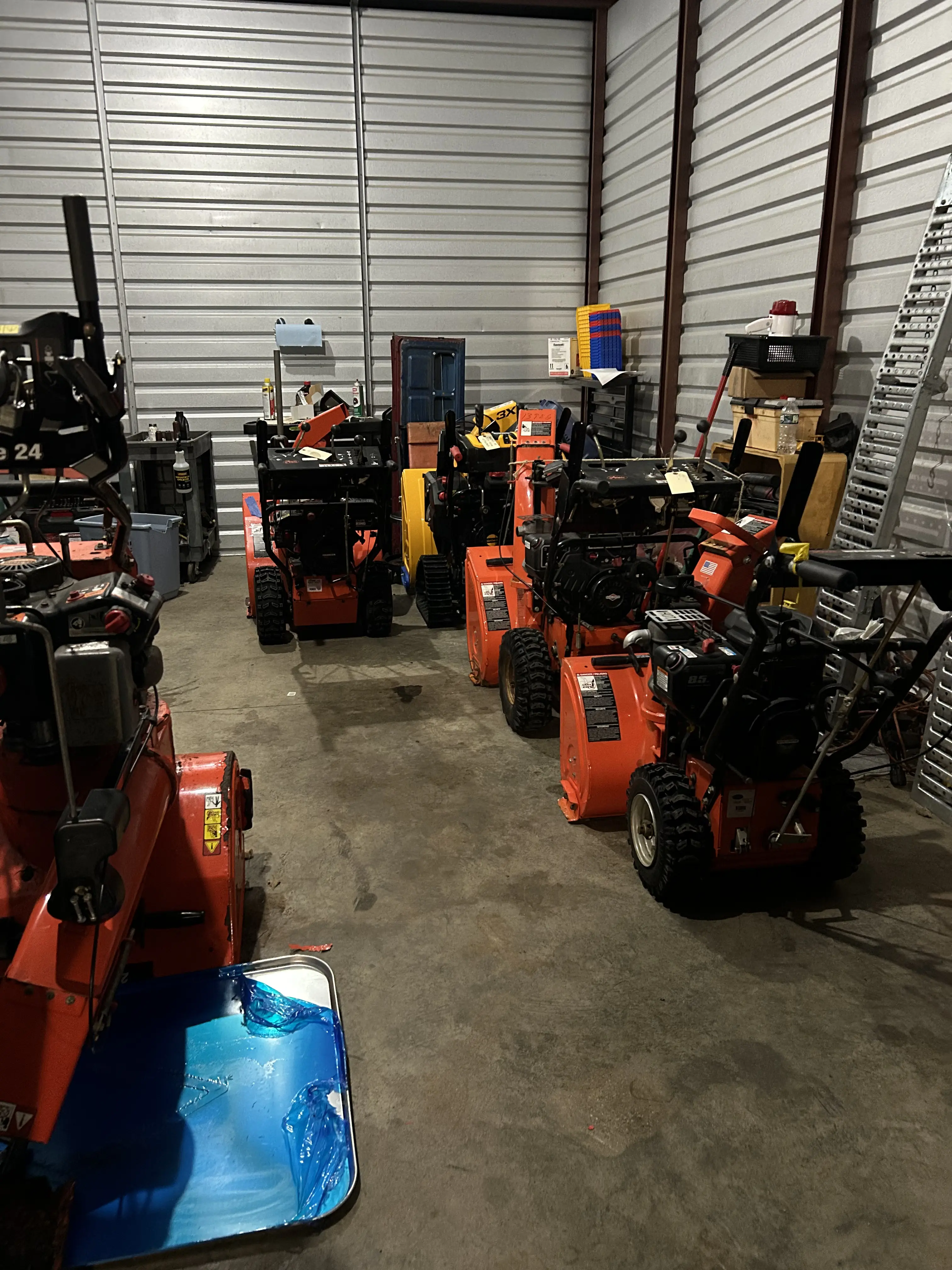 Snowblowers and outdoor equipment staged inside the shop ready for service.