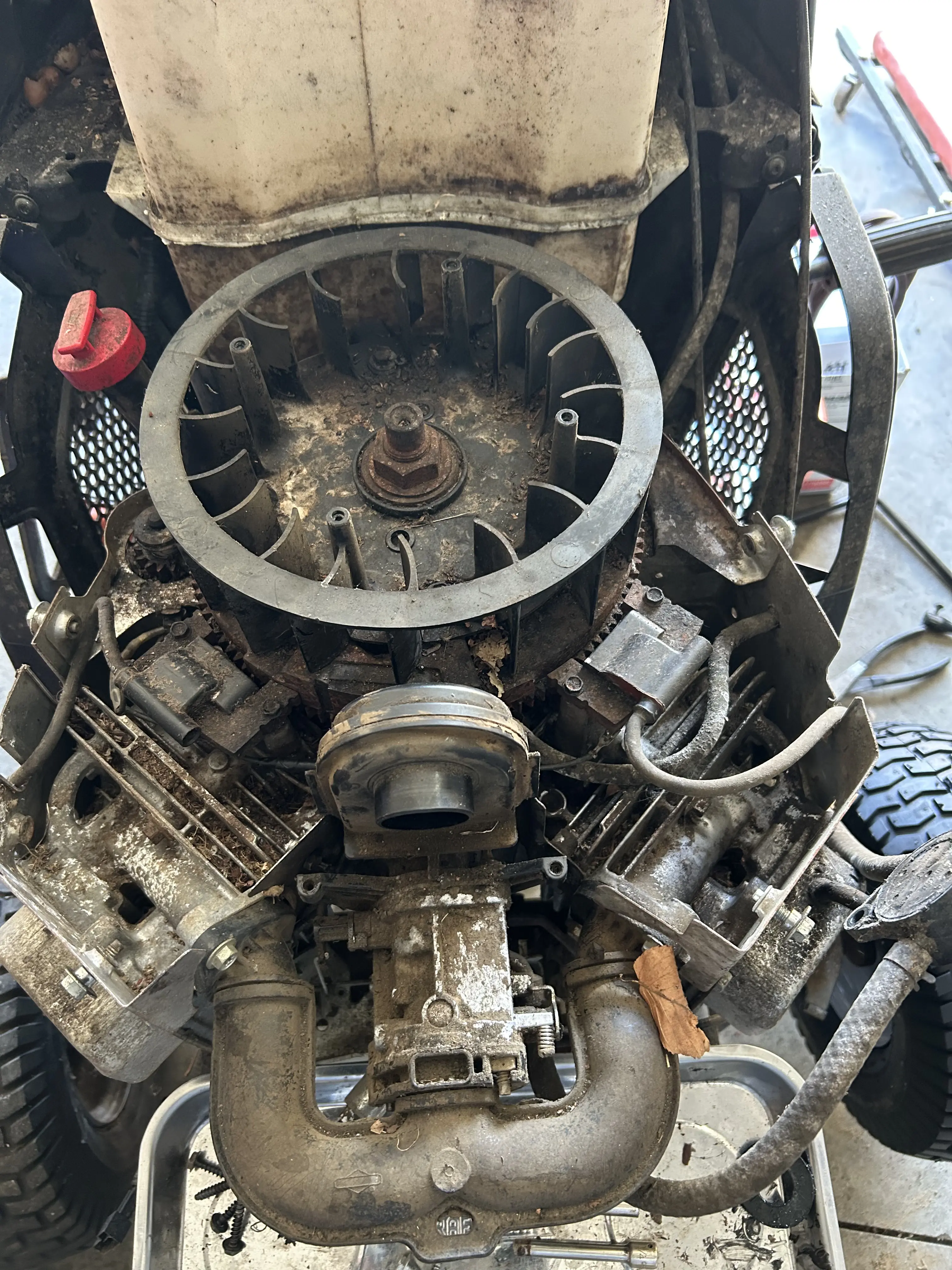 A heavily soiled small engine, mid-tear-down, with the flywheel housing and intake covered in years of grease and grass.